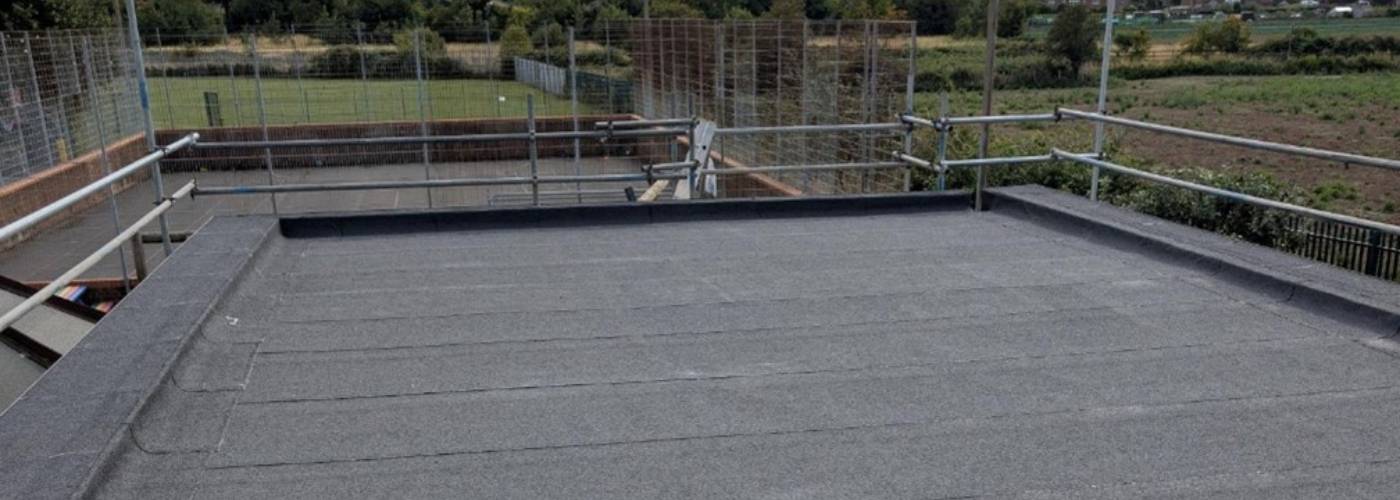 Flat roof works in progress with edge protection and scaffolding